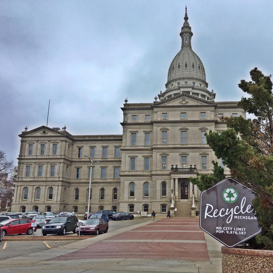 Outside of capitol building with a posed Recycle, MI indoor/outdoor sign